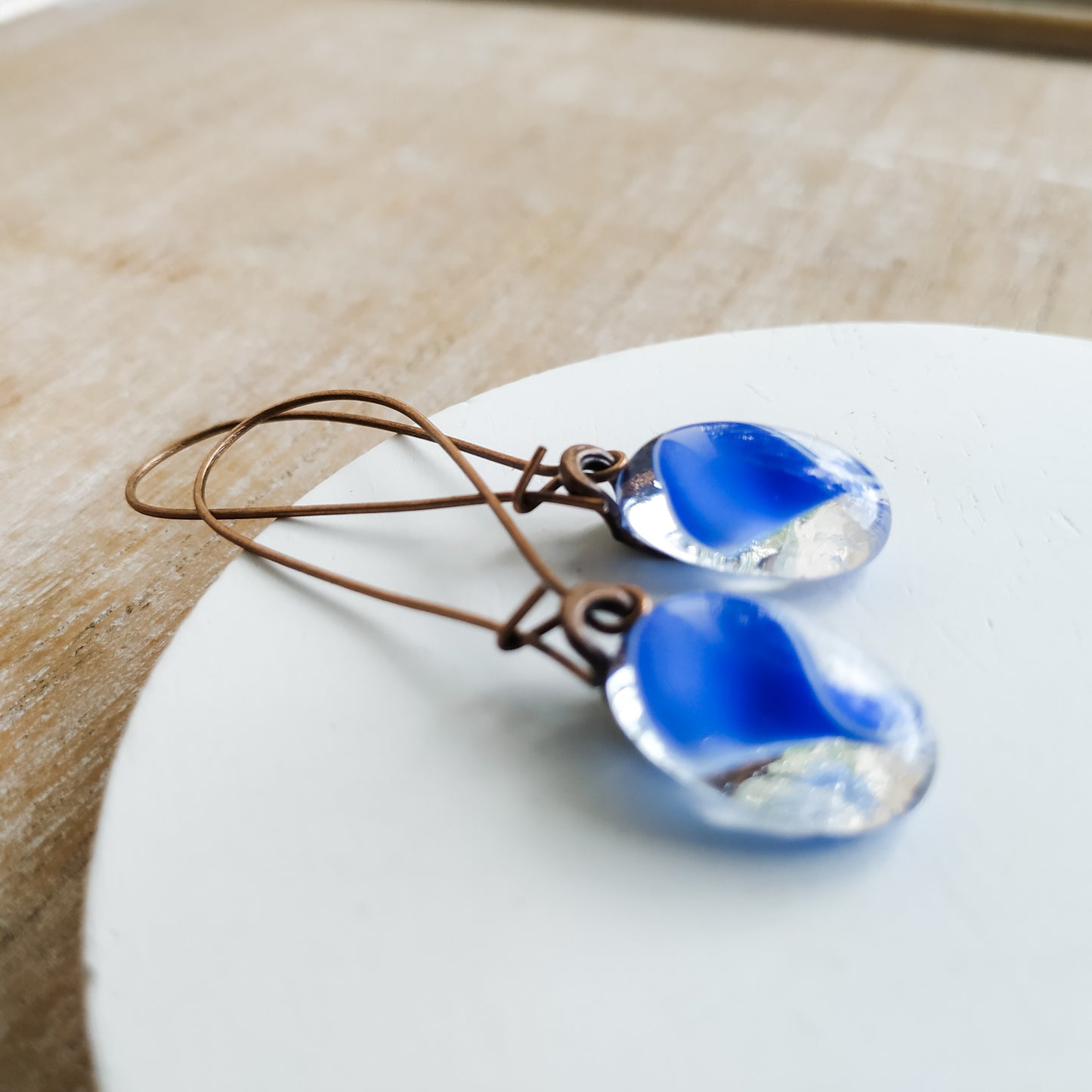 Blue glass earrings lying on a white circle 
