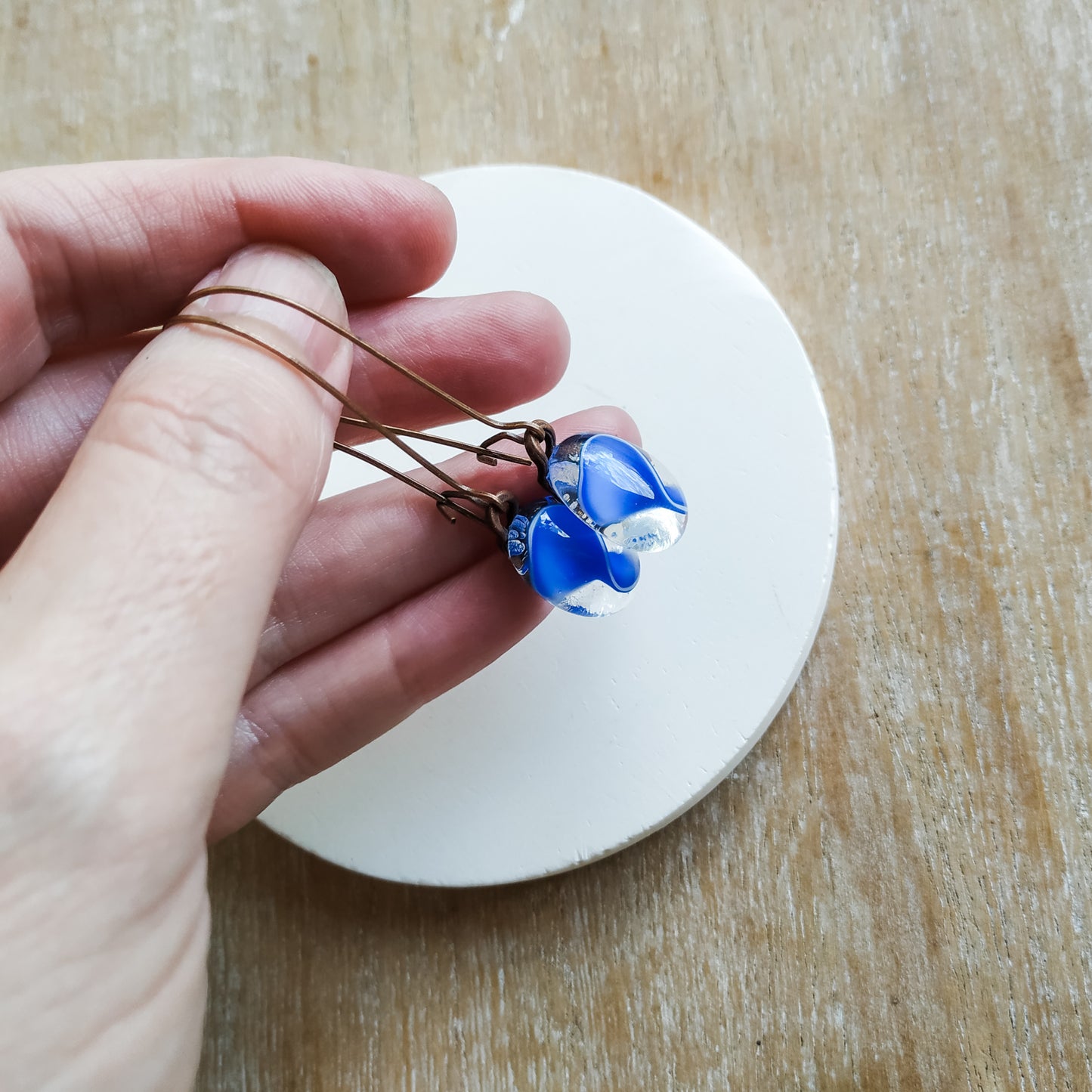 Hand holding blue earrings. handmade jewellery by Pamela Angus