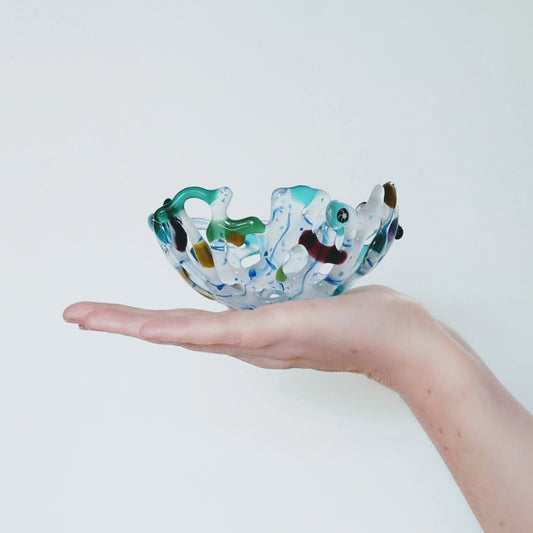 Flat hand holding bowl. art glass bowl by Pamela Angus 