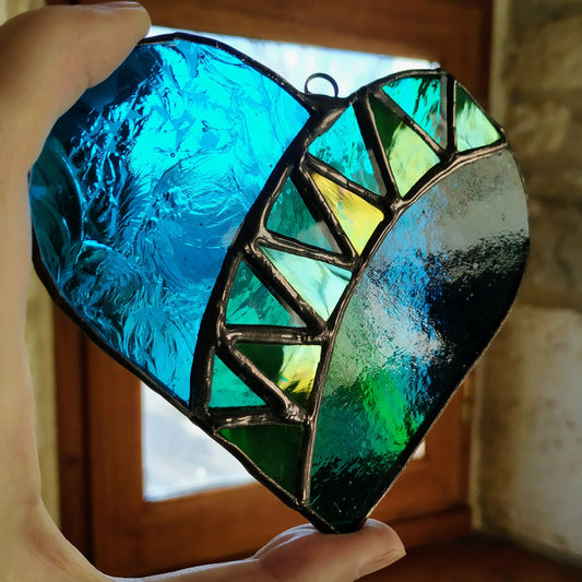 Hand holding a green and blue stained glass heart by Pamela Angus 