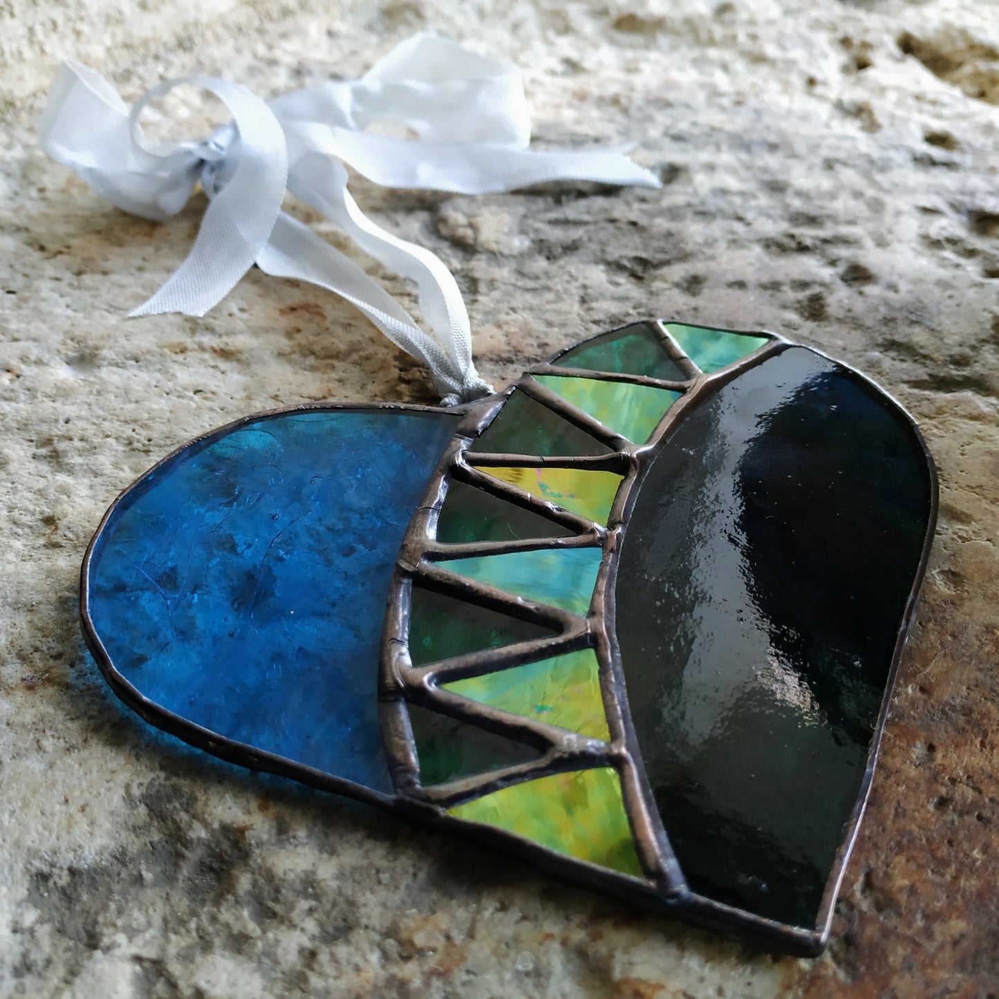 Medieval style stained glass heart lying on stone, handmade by Pamela Angus 